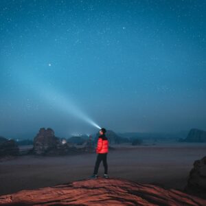 a person standing on top of a rock under a sky filled with stars